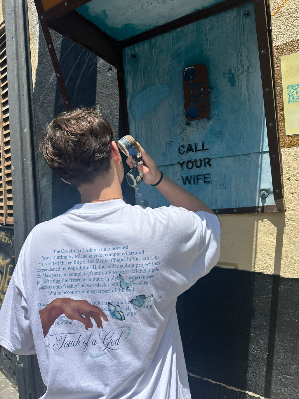 Person taking a photo of a door with text 'Call Your Wife' on a sunny day.