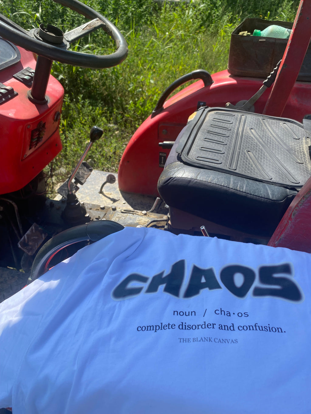 Person wearing a shirt with 'CHAOS' text sitting on a red lawn mower.