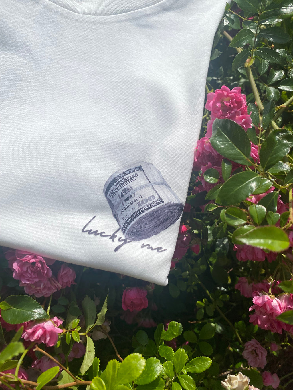 White shirt with a graphic of a money roll on a floral background
