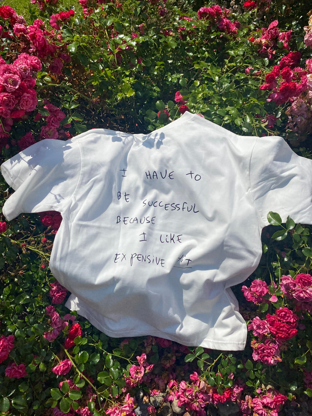 White shirt with text on a bed of pink flowers