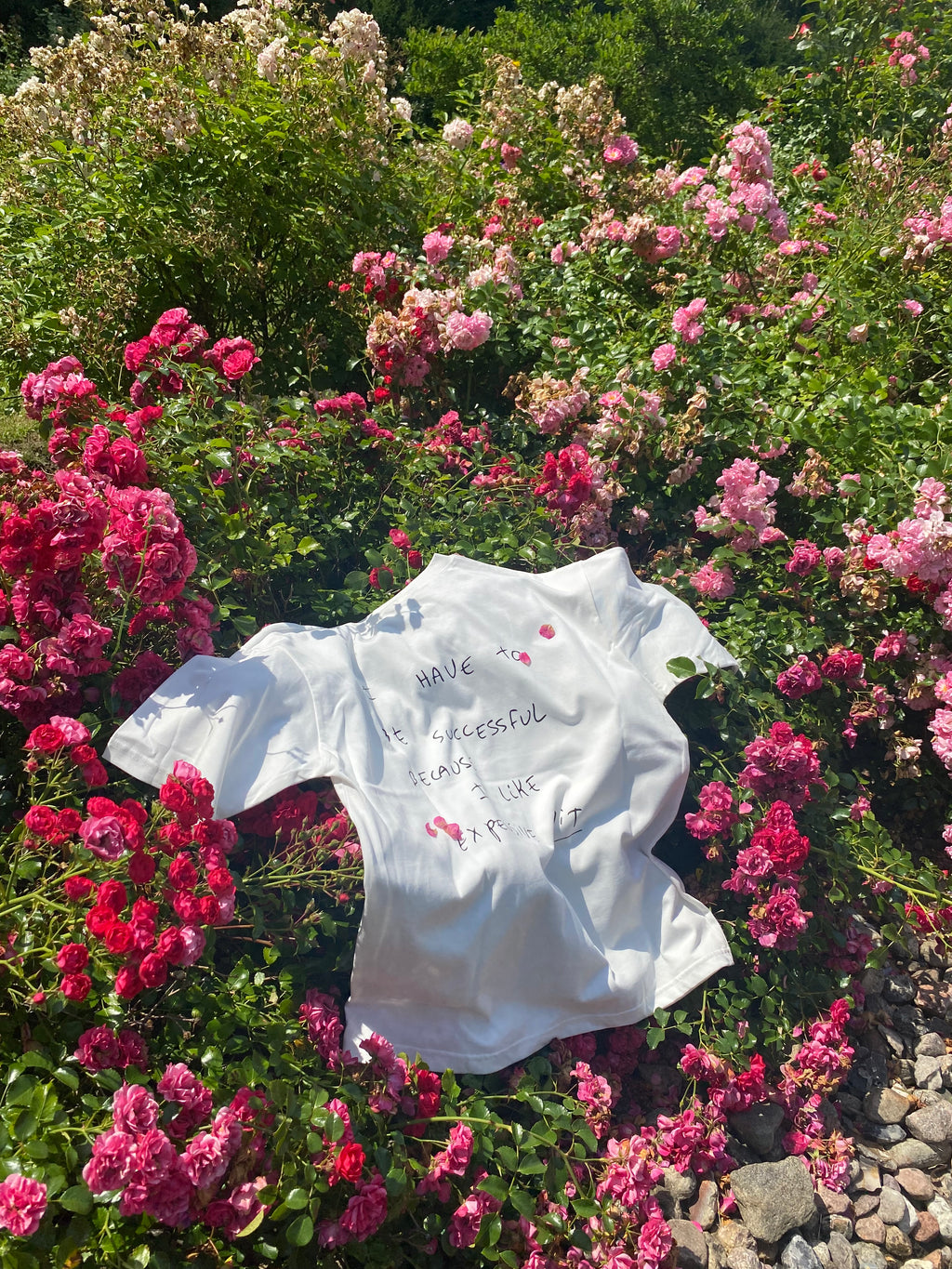 White shirt with text on a bed of pink flowers