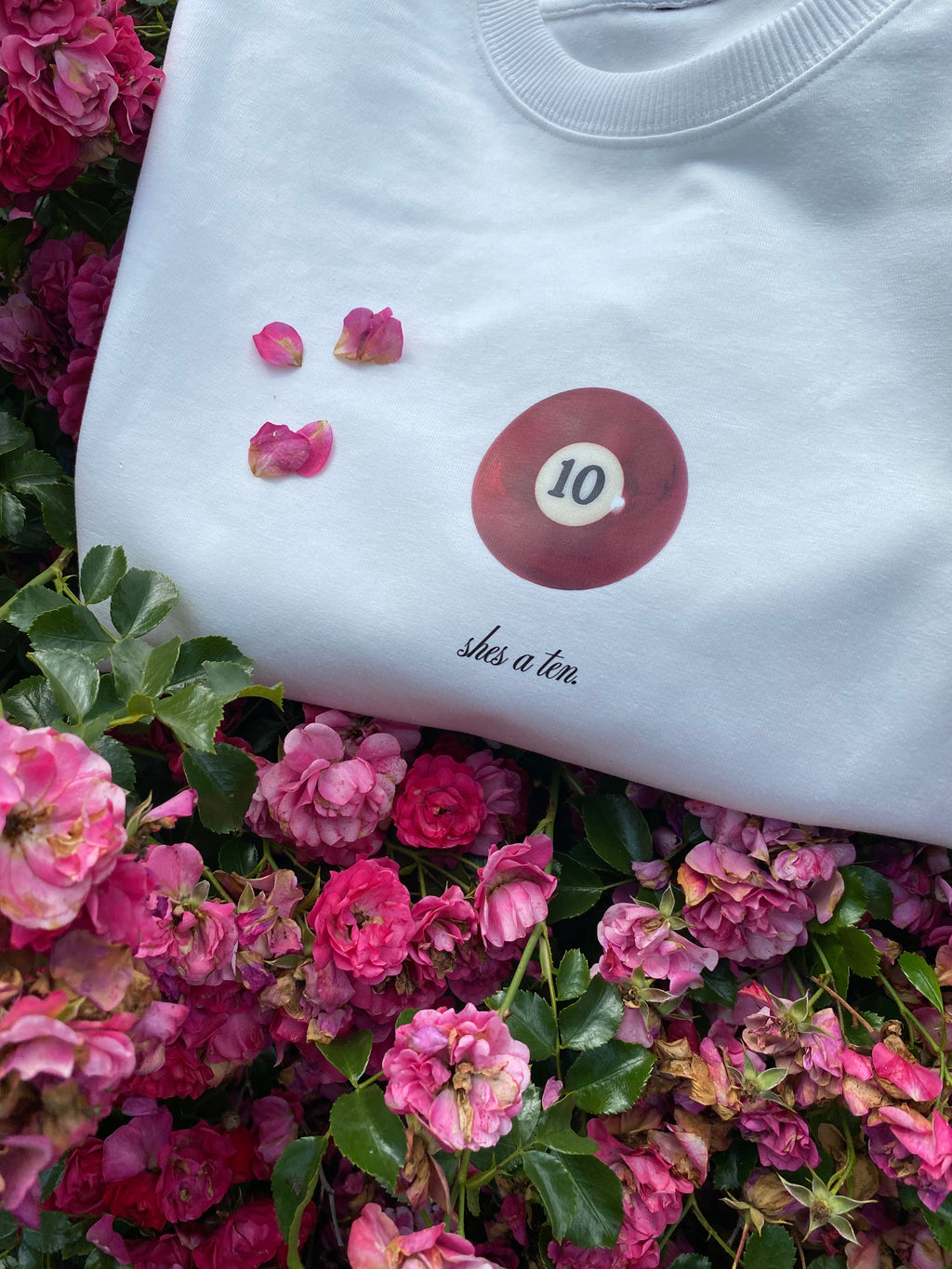 White shirt with a pool ball number '10' on a bed of pink flowers